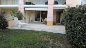 A building with a covered patio, outdoor seating, and a small garden area. - Apartment with pool and garden in Saint Aygulf (Fréjus)