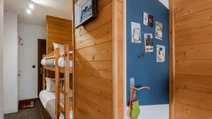 A room with wooden walls, a bunk bed, a door with a key lock, and a wall with various items pinned. - Le Nid de Châtel - Joli studio pour 4 avec balcon (Châtel)