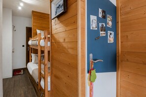 Ein Zimmer mit Holzwänden, einem Etagenbett, einer Tür mit Schlüsselsperre und einer Wand mit angehängten Gegenständen.