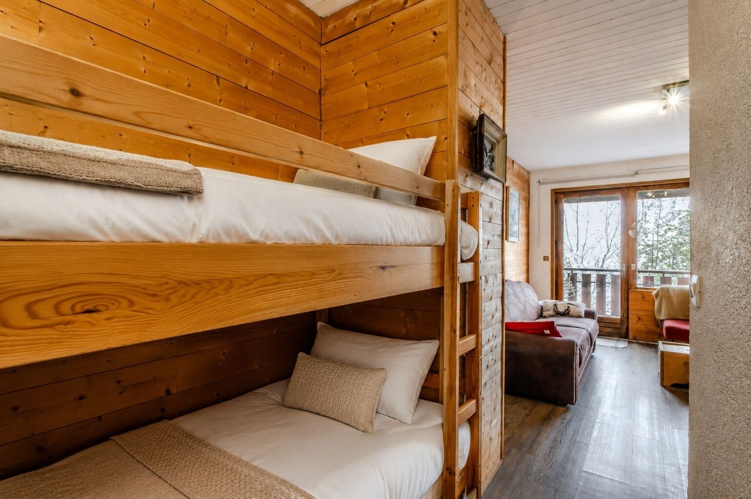 A cabin with bunk beds, a sofa, and a view of the outdoors.