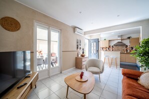 A living room with a TV, a wooden coffee table, a sofa, and a chair. - L'Horizon Doré - 500m de la Plage (Saint-Cyprien)