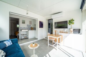A modern living space with a sofa, a dining table, a TV, and a kitchen area. - Bohème Bleue - 500m de la Plage (Saint-Cyprien)