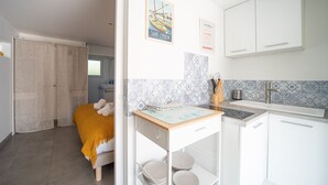 Moderni keittiö, jossa on valkoiset kaapit, pieni keittiösaareke ja laatoitettu välitila.