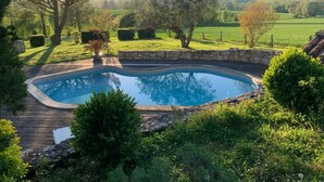 Una piscina con cubierta de madera, rodeada de abundante vegetación y árboles.