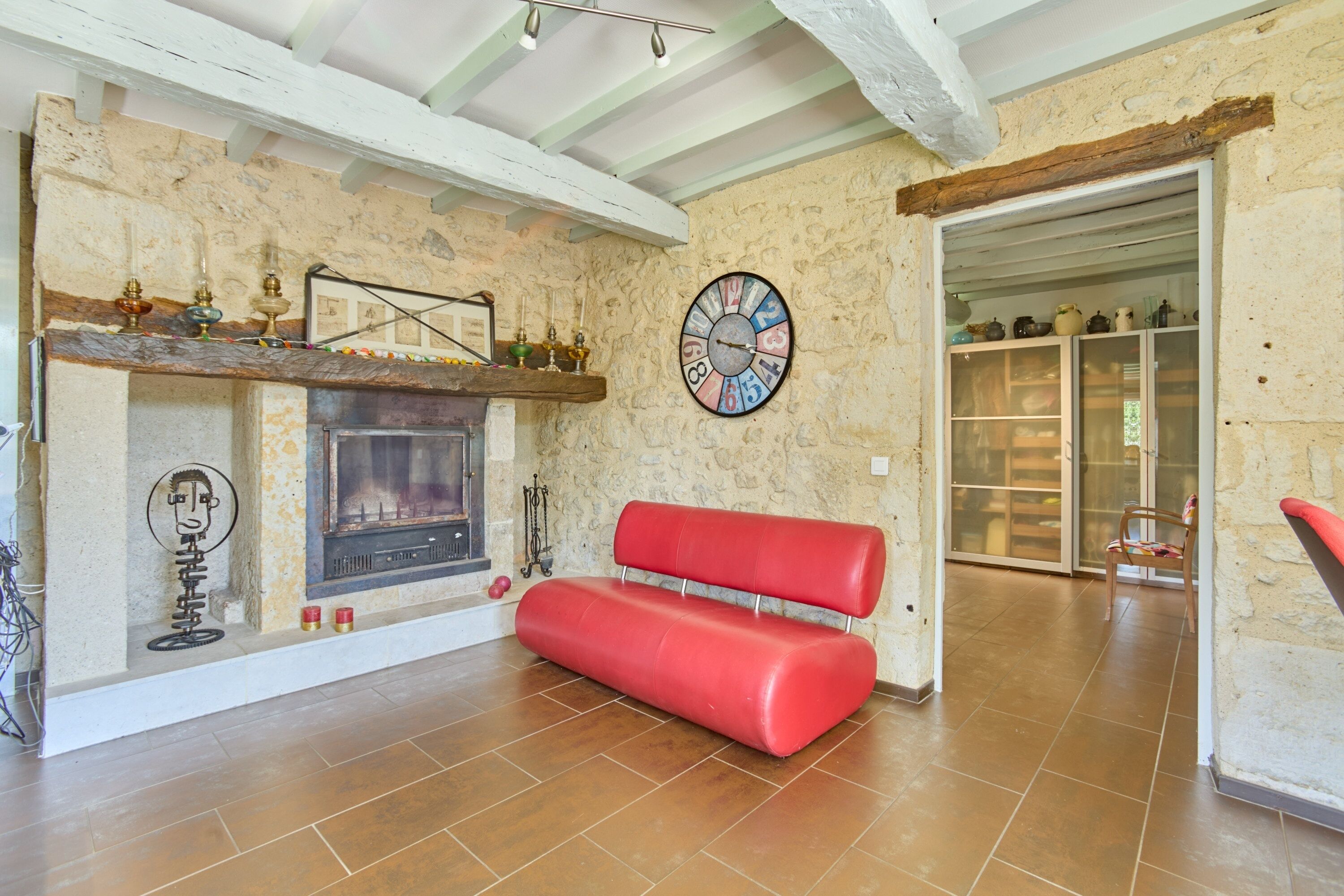 A room with a fireplace, a red bench, a wall clock, and a door leading to a balcony.