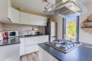 Una cucina moderna con mobili bianchi, fornello a gas, forno a microonde e frigorifero.