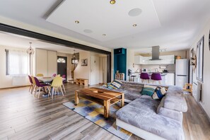 A modern living room with a sofa, coffee table, and dining area with chairs. - Le Pavillon Doulonnais - Belle maison familiale (Nantes)