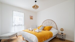 Ein Schlafzimmer mit Bett, Nachttisch, Bank und einem Fenster.