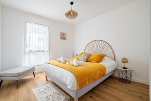 Ein Schlafzimmer mit Bett, Nachttisch, Bank und einem Fenster.