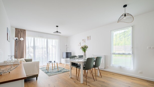Ein modernes Wohnzimmer mit Essbereich, Holzboden und großen Fenstern.