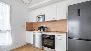 Eine moderne Küche mit weißen Schränken, einem Edelstahl-Kühlschrank, einem Geschirrspüler und einem Backofen.