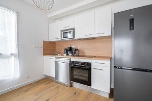 Eine moderne Küche mit weißen Schränken, einem Edelstahl-Kühlschrank, einem Geschirrspüler und einem Backofen.