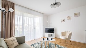 Ein modernes Wohnzimmer mit einer Couch, einem Couchtisch, einem Sessel, einem Fernseher und Kunstwerken an der Wand.