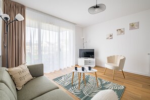 Ein modernes Wohnzimmer mit einer Couch, einem Couchtisch, einem Sessel, einem Fernseher und Kunstwerken an der Wand.