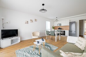 Ein modernes Wohnzimmer mit Fernseher, Sofa, Couchtisch und Essbereich.