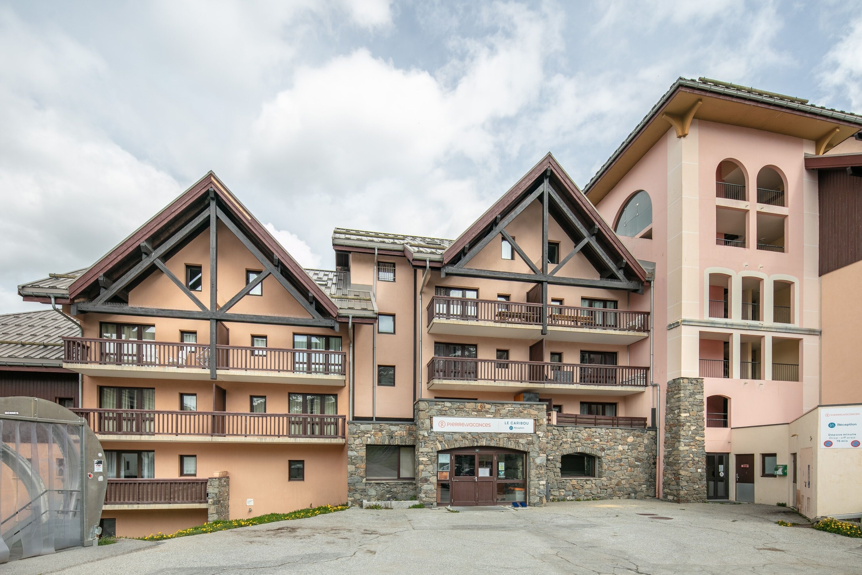 A multi-story hotel with balconies, a stone facade, and a sign for 'Pierre Voinces.'