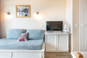 A bedroom with a bed, a television on a stand, a small white cabinet, and a framed picture on the wall. - Le Thabor Caribou - À 650 m des pistes (Valmeinier)