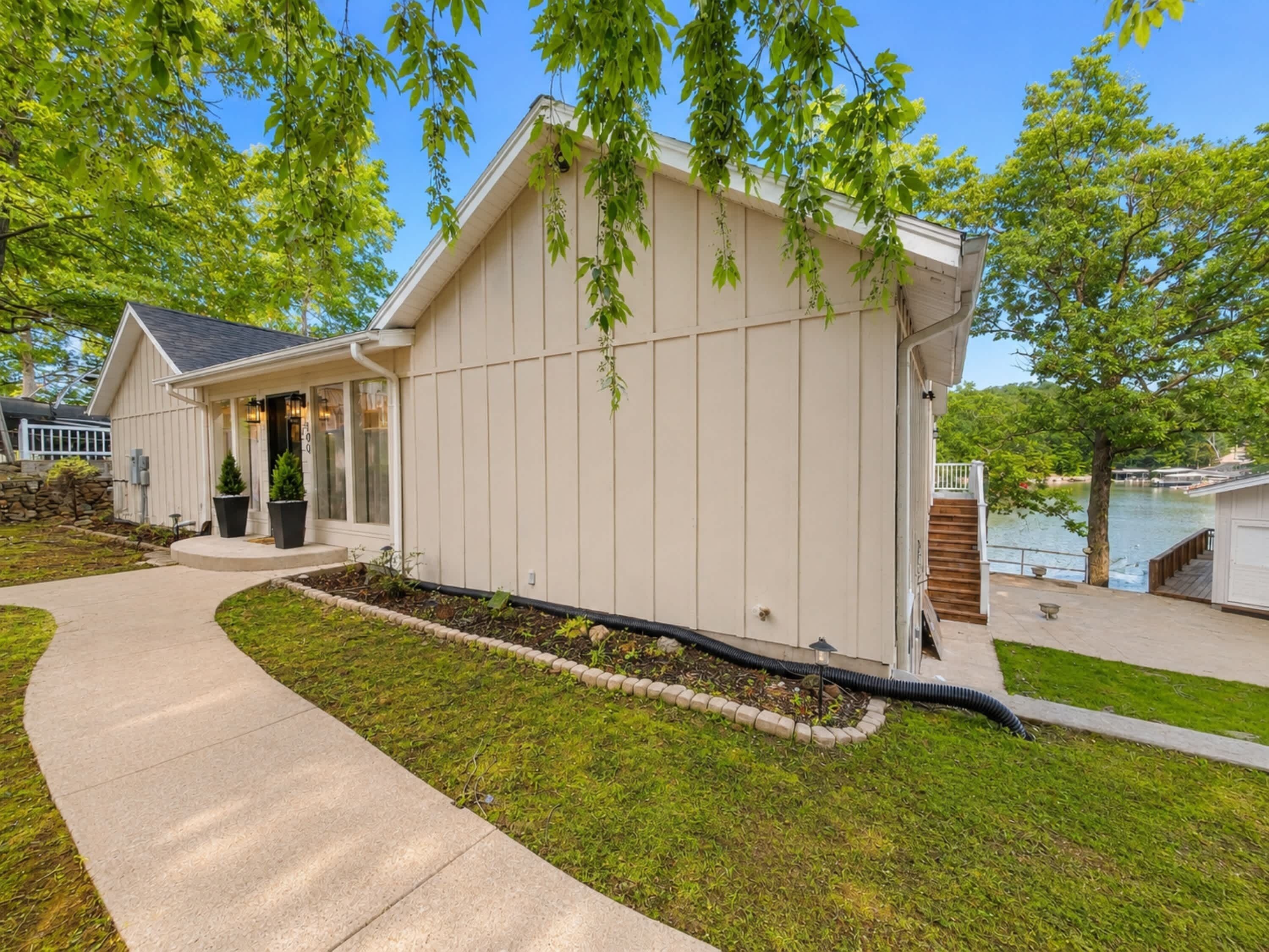 A house with a covered porch, a pathway, and a view of a body of water.