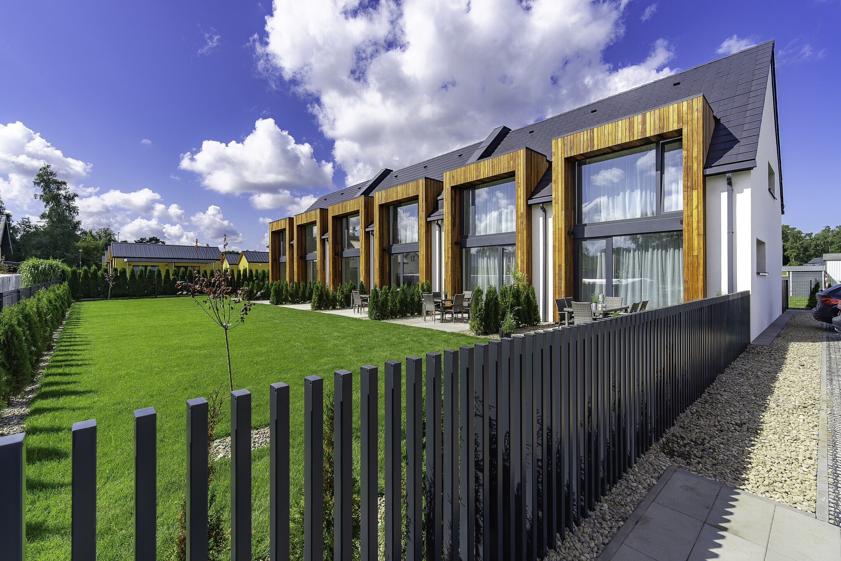 Un bâtiment moderne doté de grandes fenêtres, d’une pelouse bien entretenue et d’une clôture en bois.