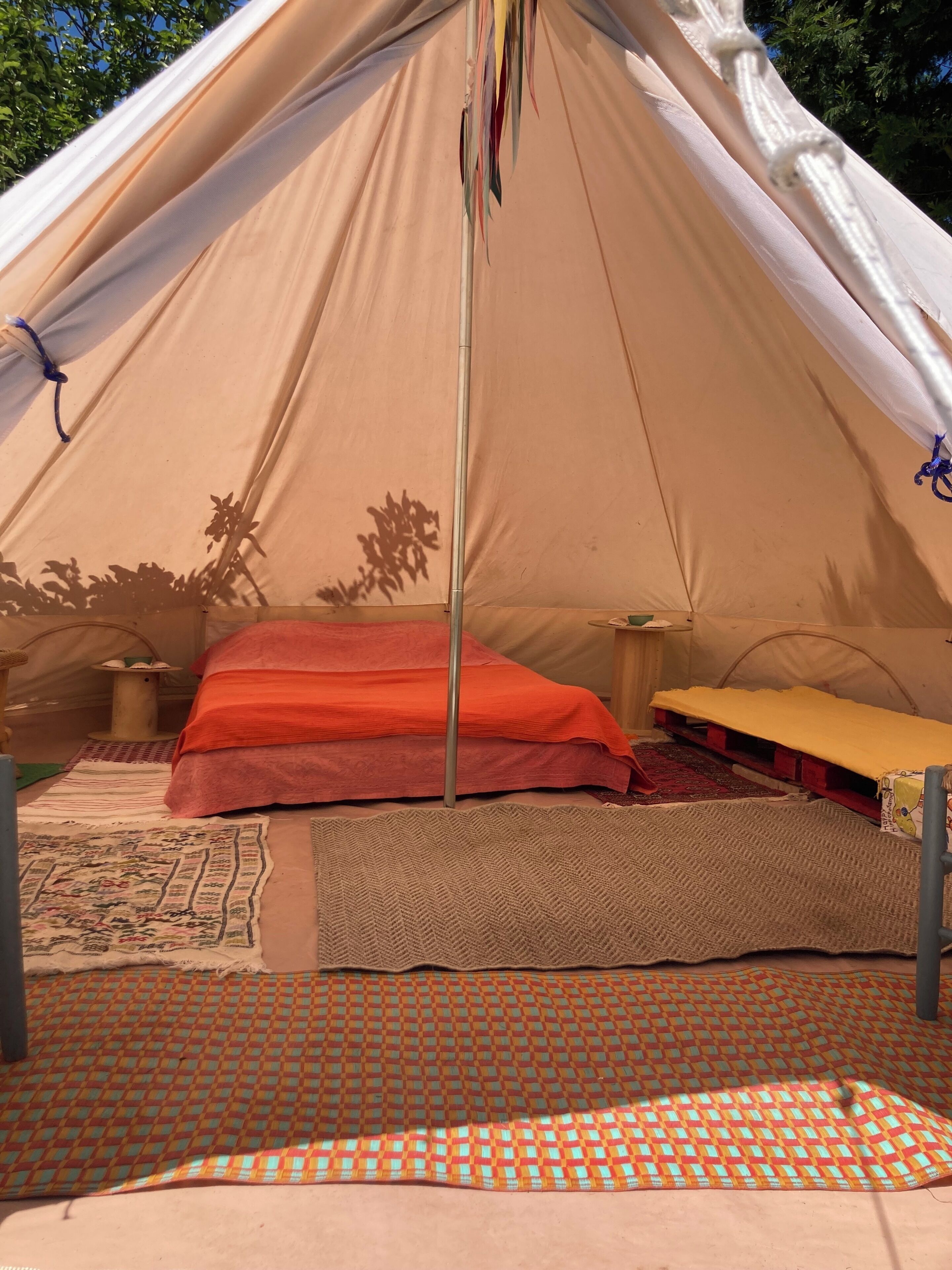 A tent with a bed, a table, and a hanging item.