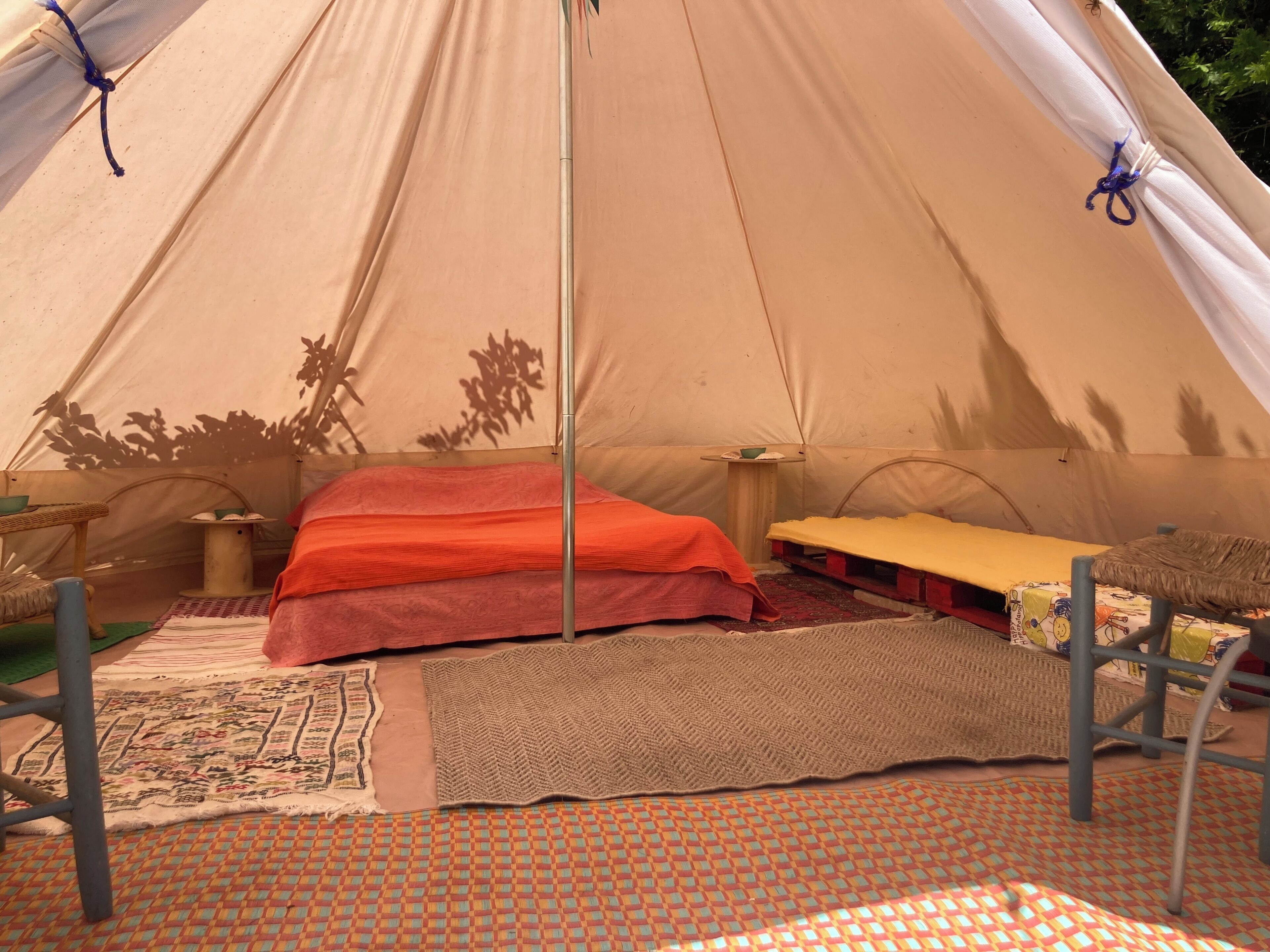A tent with a bed, a table, and a chair.