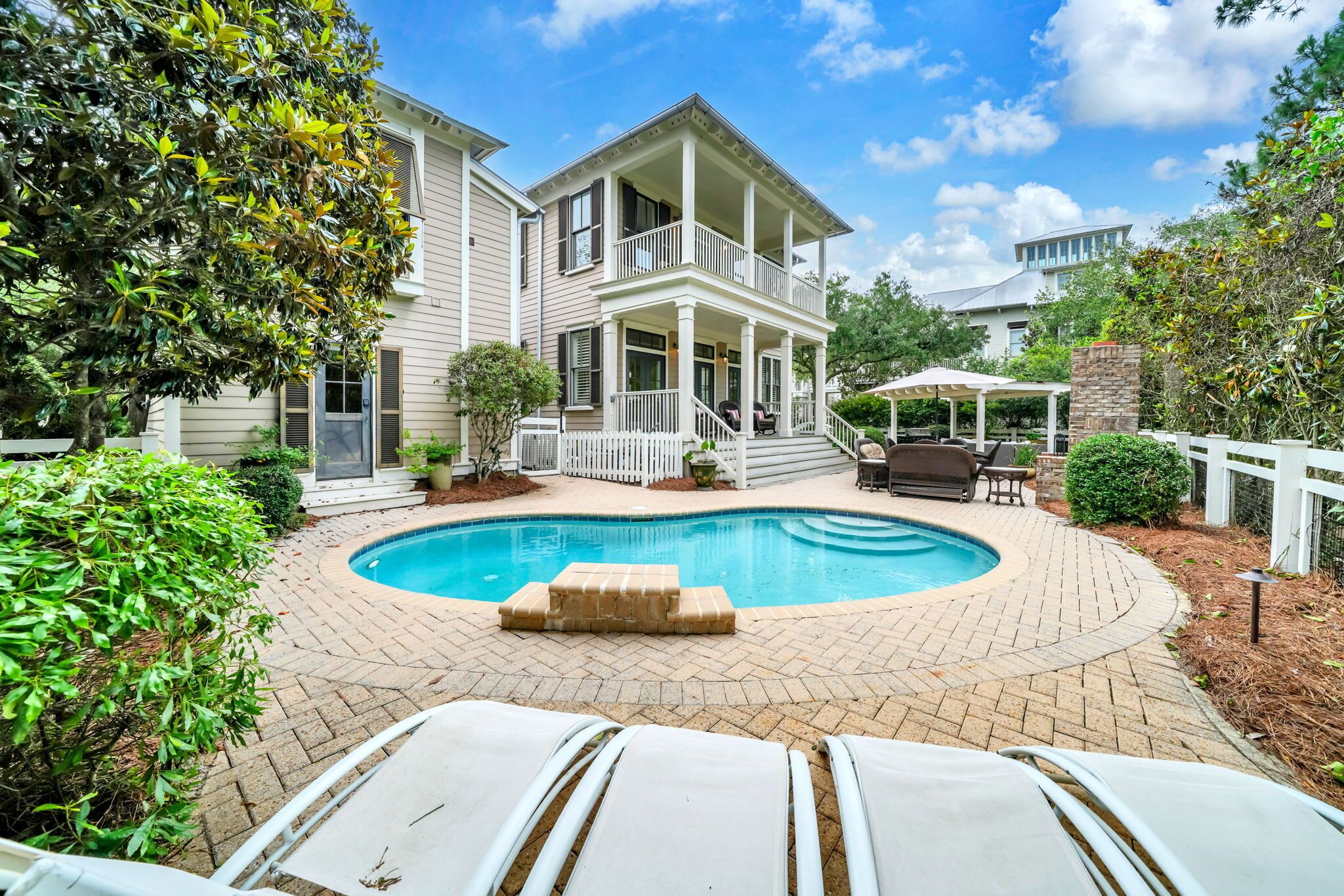 A two-story house with a pool, outdoor seating, and a covered patio.