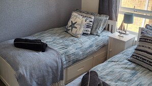 Une chambre avec deux lits, une décoration murale en forme d’étoile, une décoration murale en forme d’étoile de mer, une fenêtre avec des rideaux et une table de chevet avec une lampe.