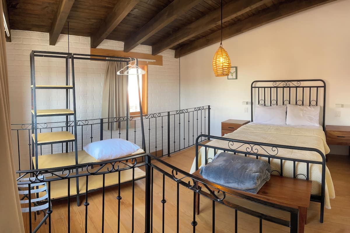 Una habitación con una cama litera, un escritorio, una lámpara colgante y una ventana con cortinas.
