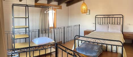 A room with a bunk bed, a desk, a hanging light fixture, and a window with curtains.