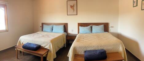 A room with two beds, wooden benches, a wooden ceiling, and a framed picture on the wall.