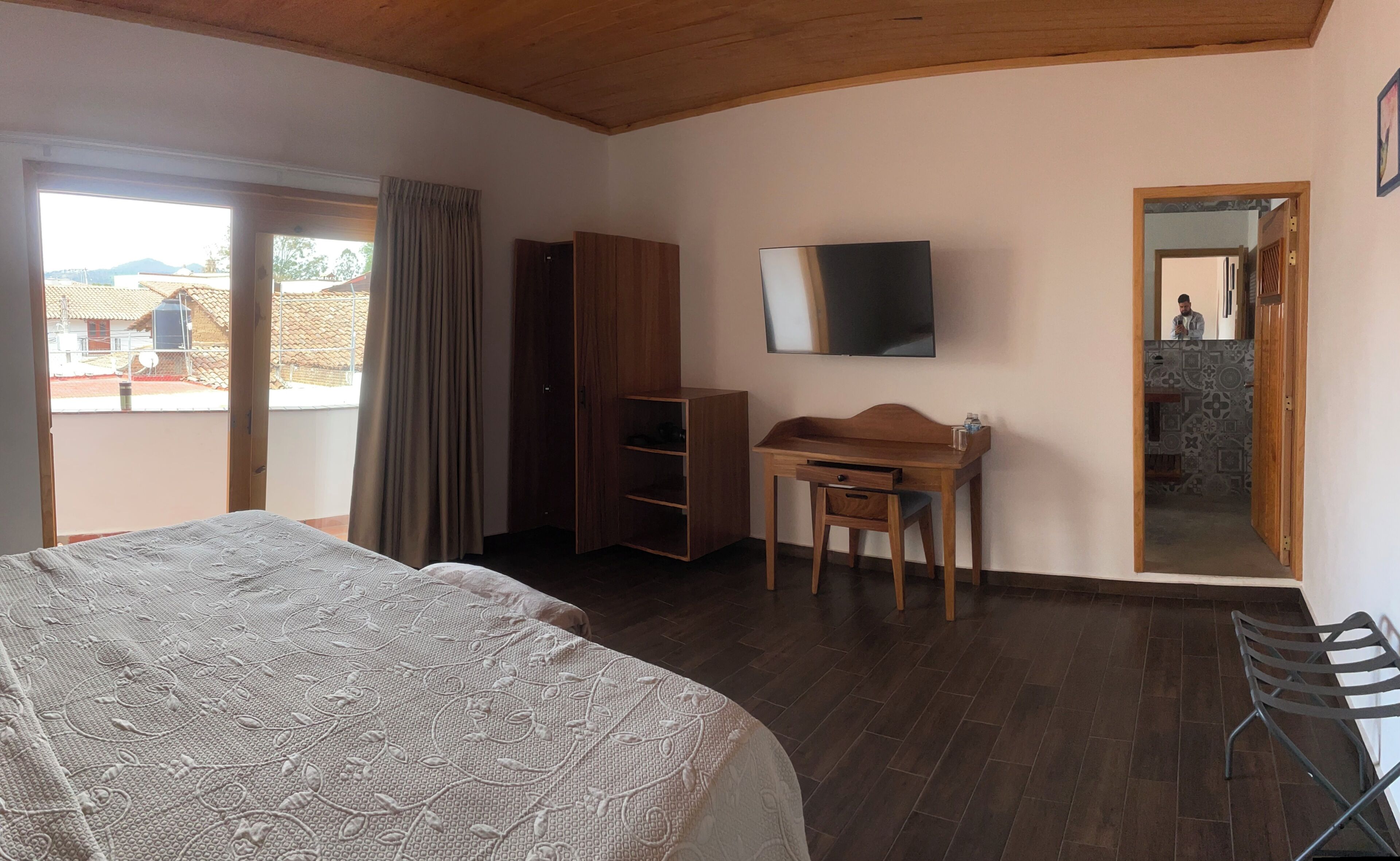Un dormitorio con cama, escritorio, silla, televisor y armario.