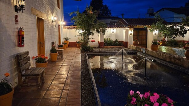 Un patio con piscina, bancos, plantas en macetas y un extintor.
