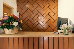 A reception desk with a herringbone-patterned wall, a wicker basket with flowers, and a glass vase with flowers. - Tapalpa Hotel Casa Colibrí (Tapalpa)