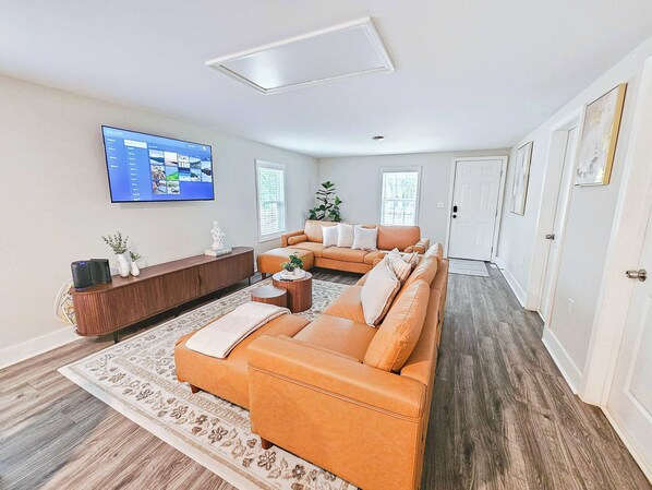 Uma sala de estar com sofá, mesa de centro, televisão e um aparador.