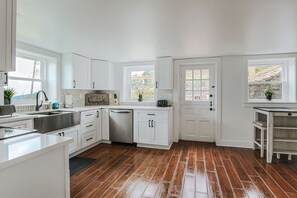 A kitchen with white cabinets, a stainless steel sink, and a wooden floor. - Swannanoa Guest House: Stunnning Mountain Views (Afton)