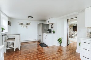 A modern kitchen with white cabinetry, a stainless steel refrigerator, and a coffee machine.