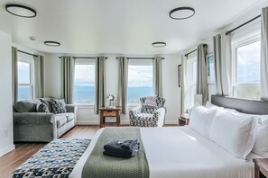 Ein Hotelzimmer mit Bett, Sofa, Stuhl und Blick auf die Berge.