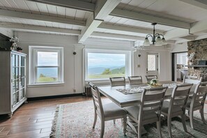 Ein Esszimmer mit großem Tisch, Stühlen und Blick ins Freie.