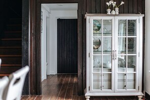 Une pièce avec une porte en bois foncé, un meuble blanc aux portes vitrées et un sol carrelé.