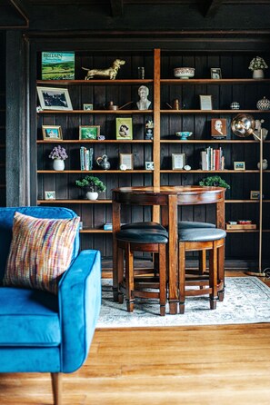 A room with a blue armchair, a wooden coffee table, and a bookshelf filled with books, decorative items, and a globe.