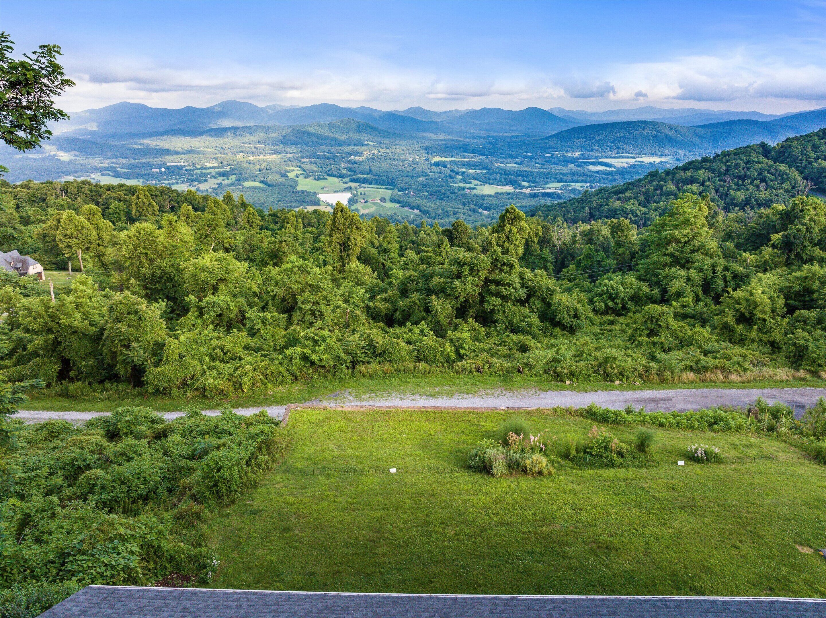 Un paysage verdoyant et luxuriant, avec une route, des arbres denses et des montagnes à l’horizon.