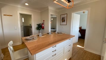 Una cocina amplia con encimera de madera, armarios blancos y una lámpara colgante.