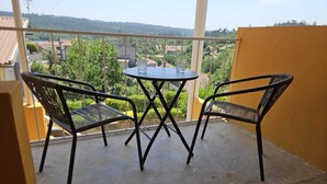 Ein Balkon mit zwei Stühlen und einem Tisch, mit Blick auf eine Wohngegend.