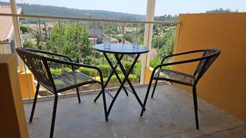 Un balcón con dos sillas y una mesa, con vista a una zona residencial.