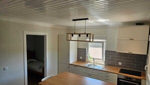 Eine kompakte Küche mit Holztisch, weißen Schränken, einem eingebauten Backofen und einem Fenster mit Blick.