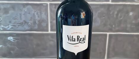 A bottle of Vila Real wine on a cork coaster with a nameplate reading 'Casa da Laranjeira'.