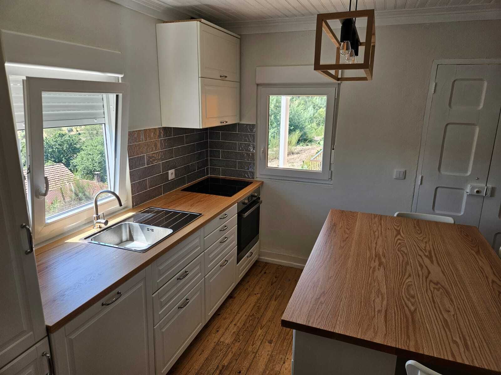 A kitchen with a wooden countertop, a sink, a window, and a door.
