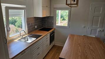 A kitchen with a wooden countertop, a sink, a window, and a door.