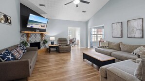 A spacious living room with a flat-screen TV, ceiling fan, and hardwood floors. - 4BR Foley Home Near OWA and Beaches (Foley)