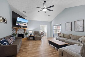 A spacious living room with a flat-screen TV, ceiling fan, and hardwood floors. - 4BR Foley Home Near OWA and Beaches (Foley)